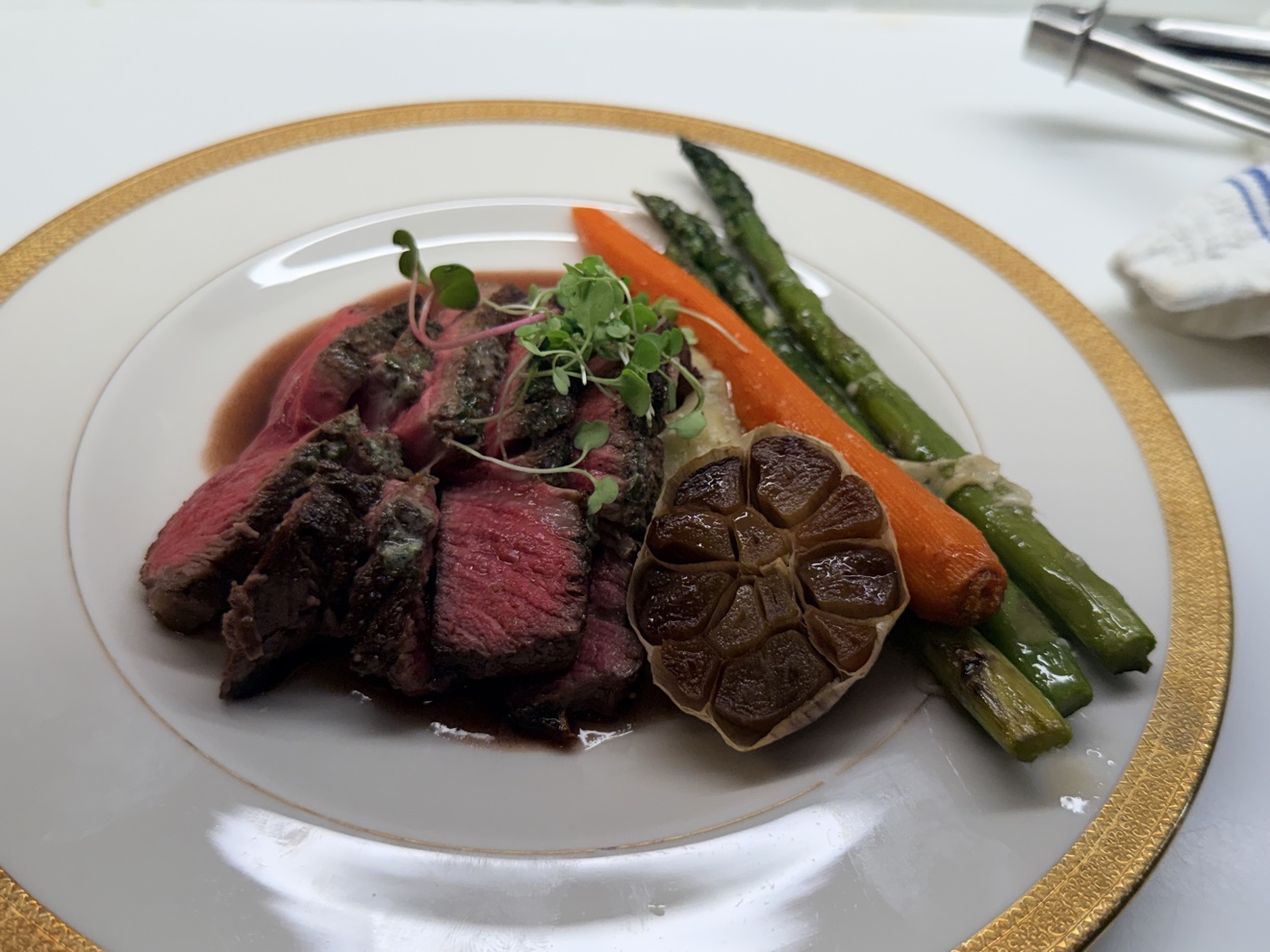 Sliced beef tenderloin plated with asparagus and roasted garlic