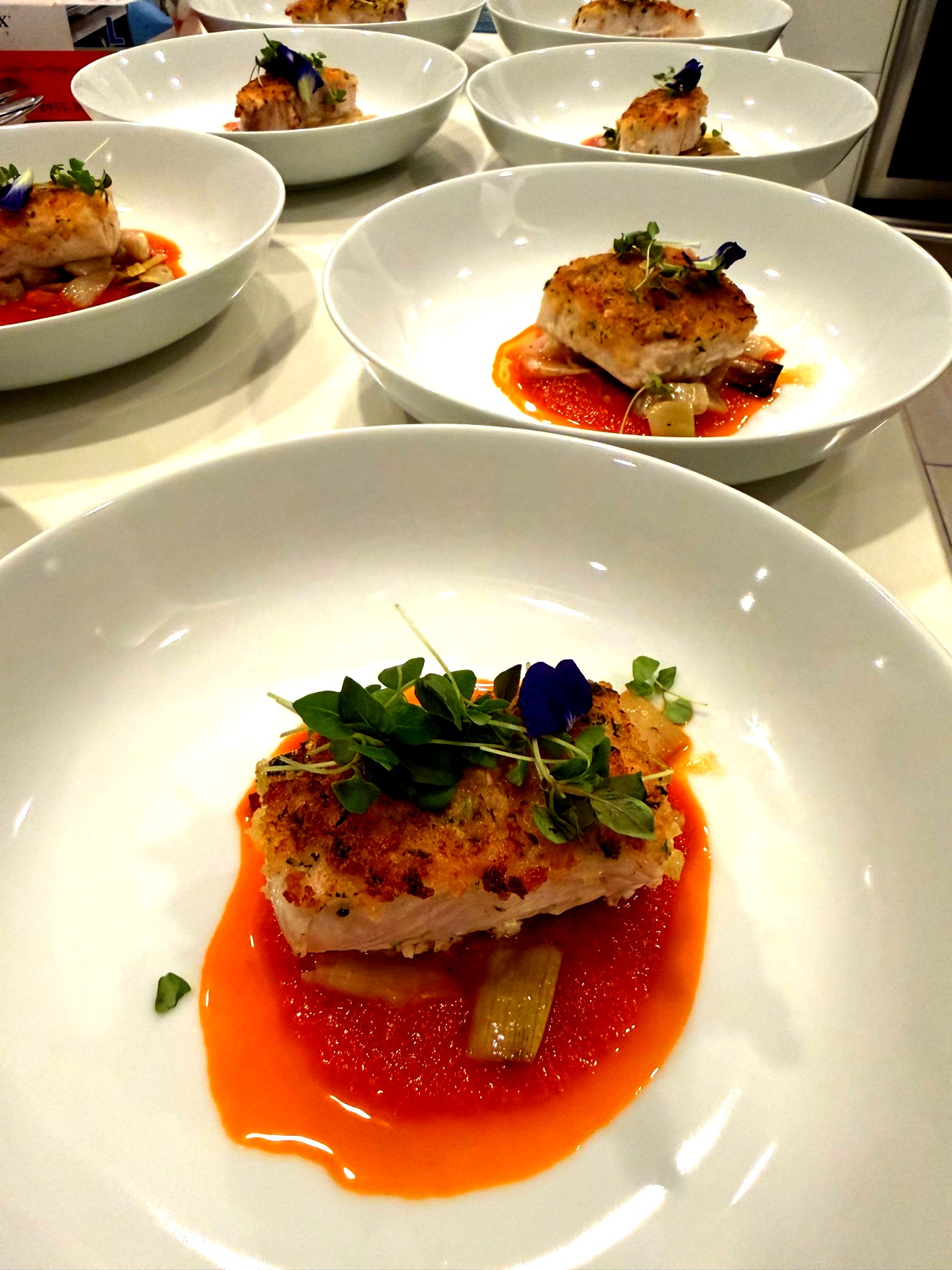 Herb-crusted fish with tomato fennel sauce and edible flowers