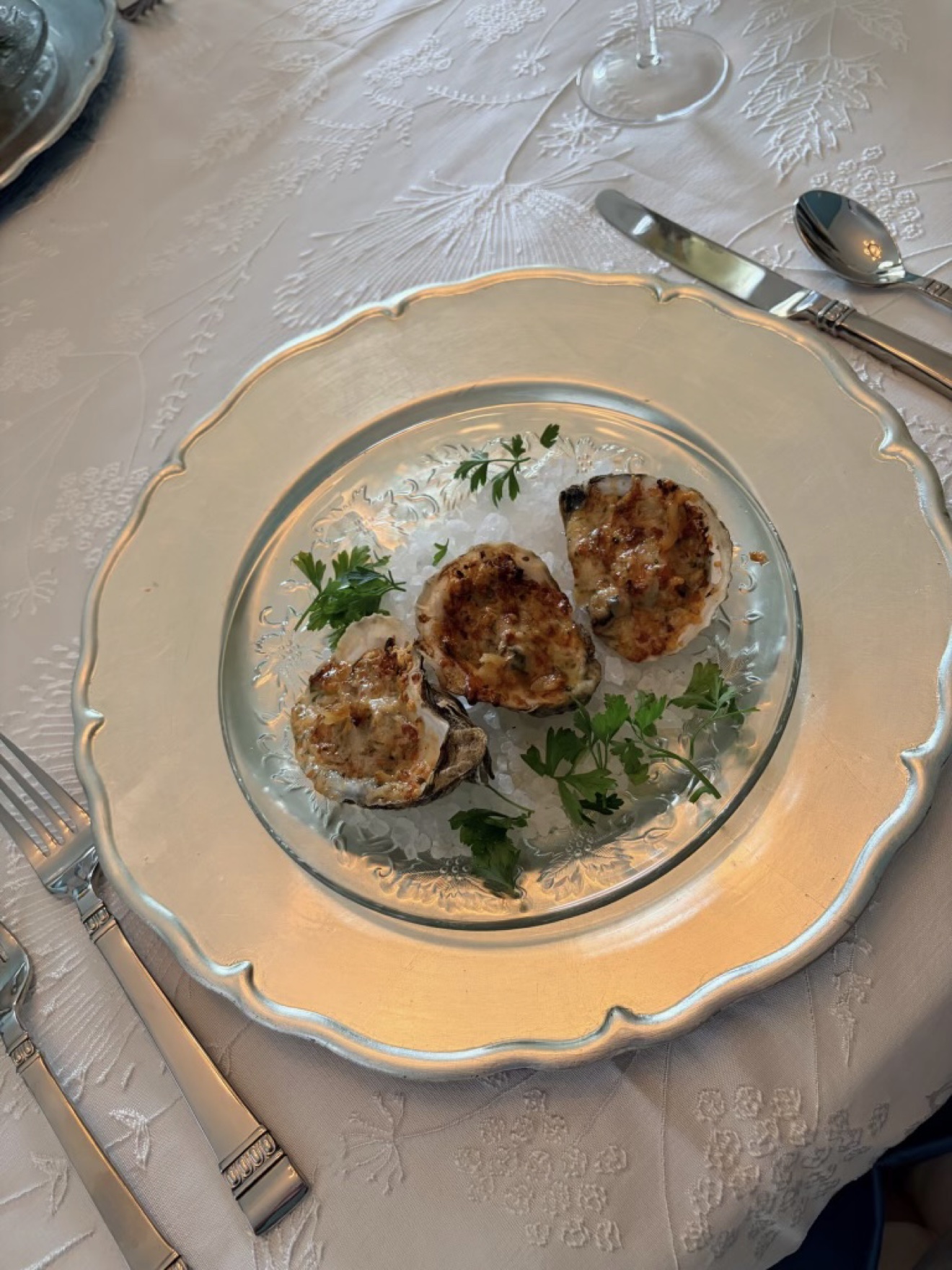 Baked oysters served on ice in a formal table setting