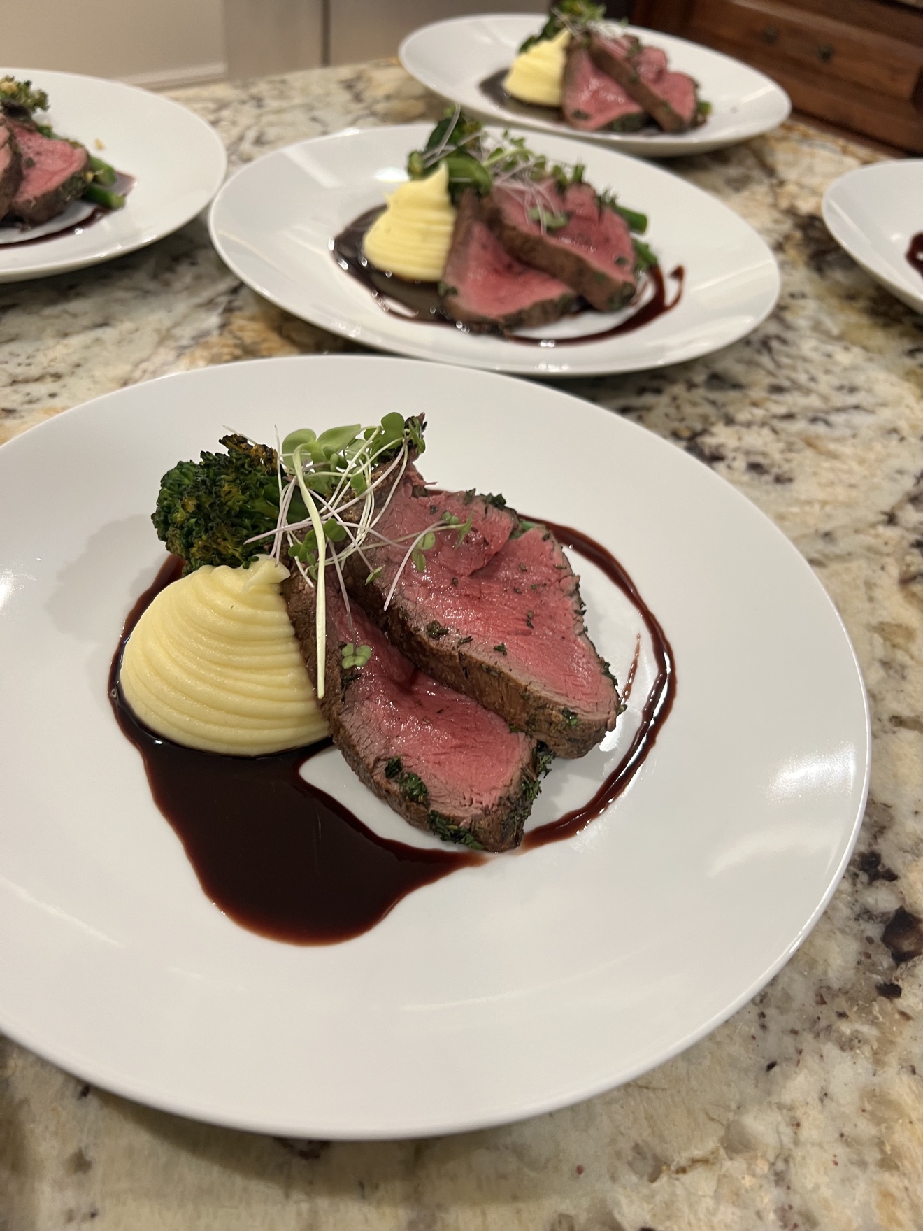 Sliced herb-crusted beef tenderloin with pomme purée and red wine jus